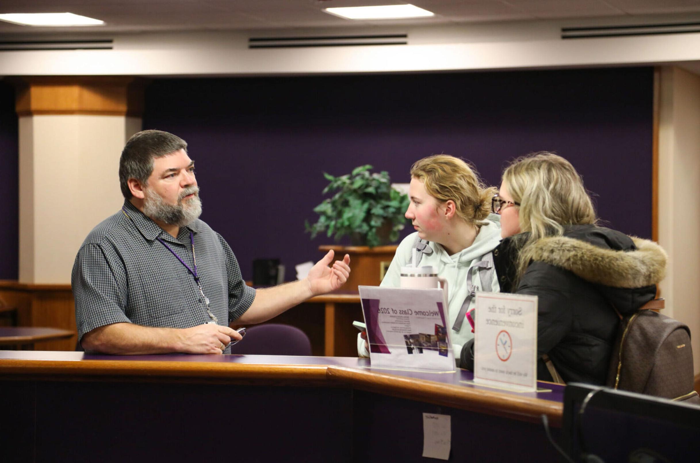 IT Director Tom Steffes talks with two students at the Help Desk